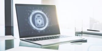 A laptop with a lock on the screen sits on a desk. 