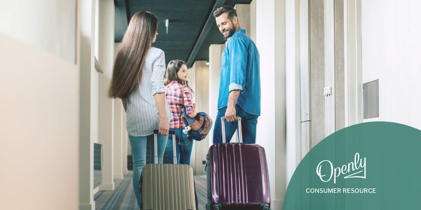 Two parents and their daughter carry luggage down a hallway.
