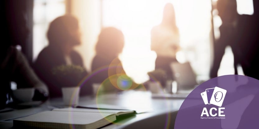 Three people sit around a table in a sunlit room.