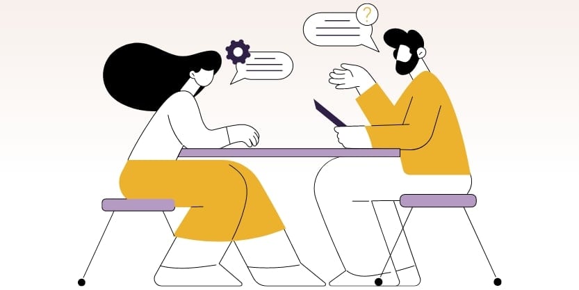 Two people sit at a table having a discussion. 