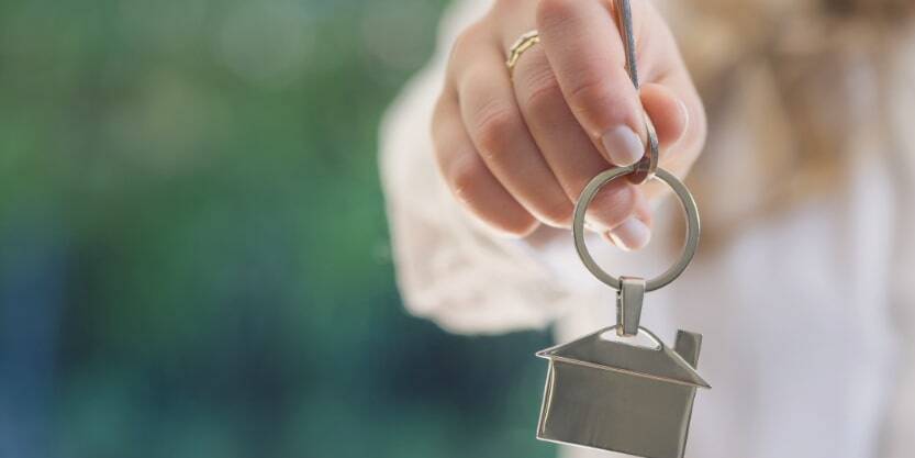 A hand holds a keyring of a house