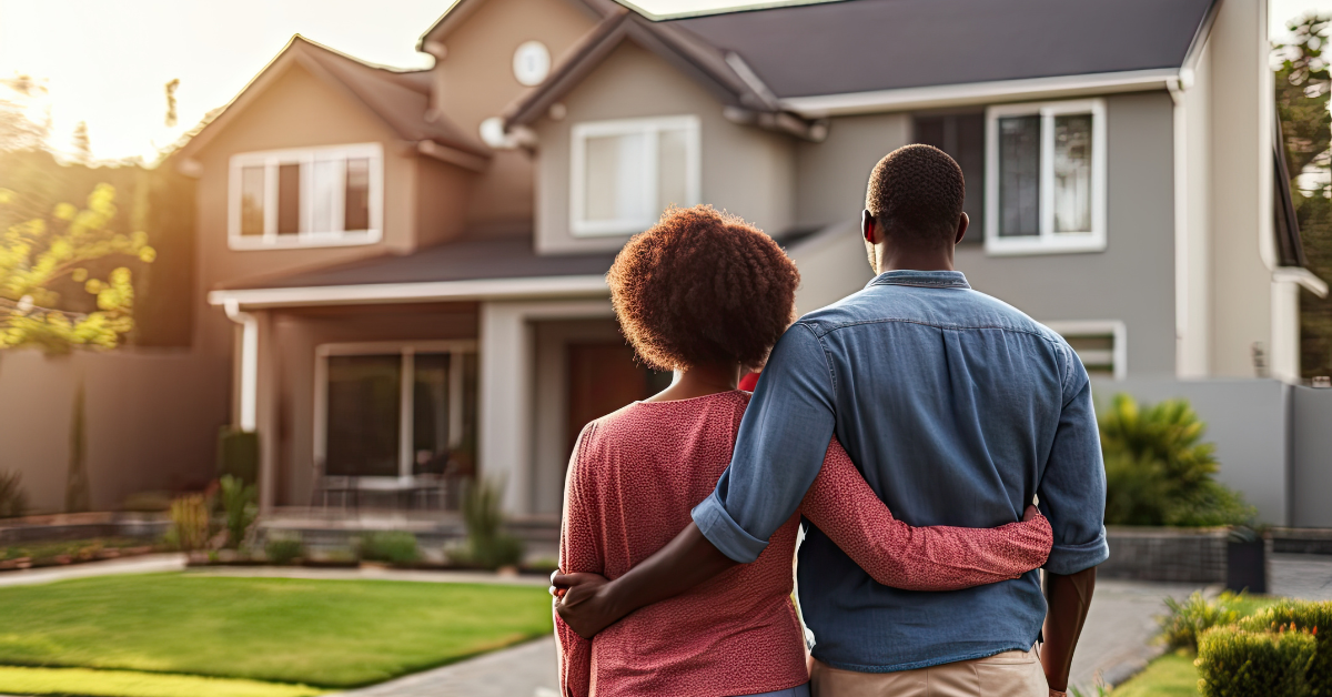 A hugging couple looks at a house.